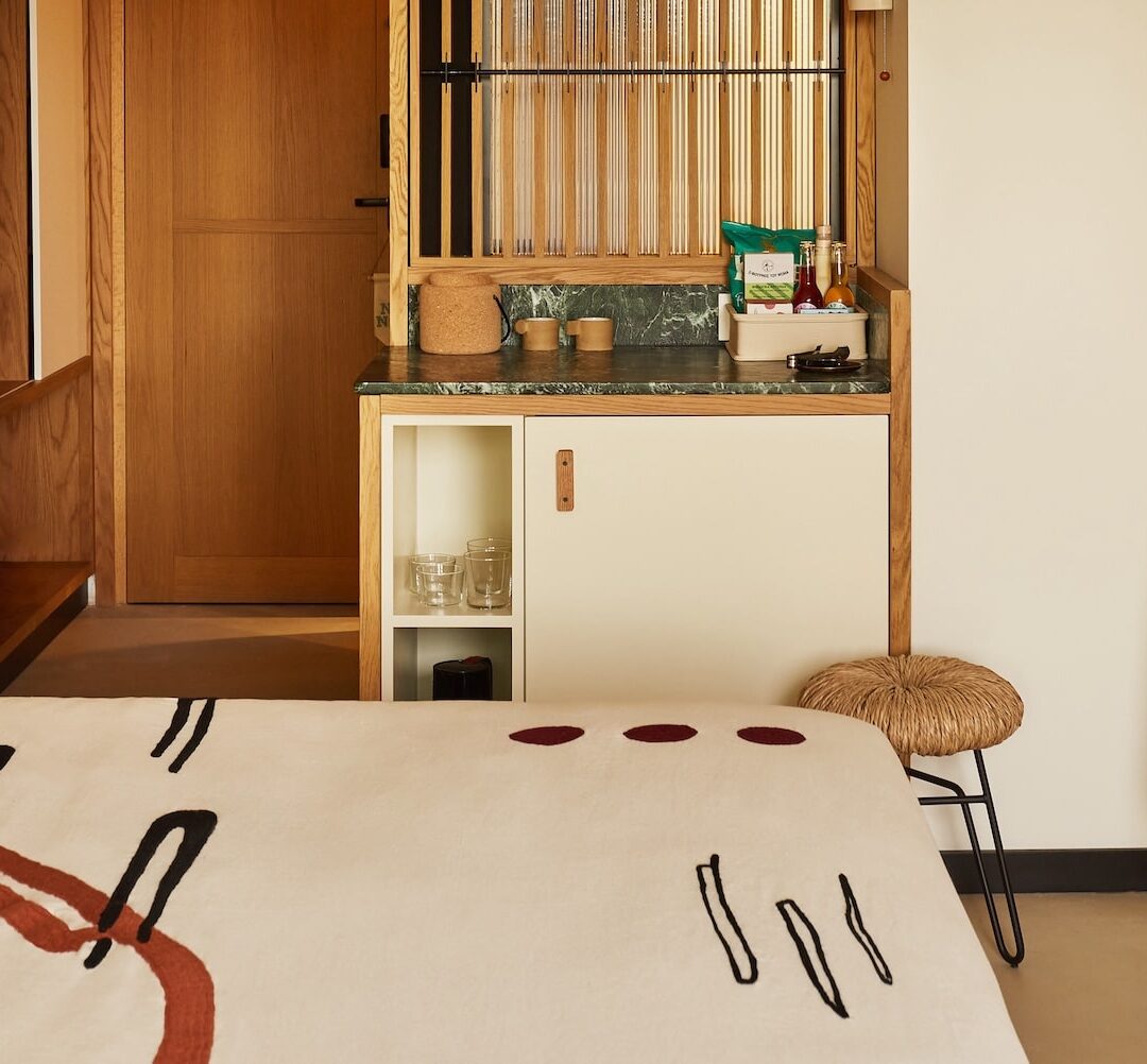 A small bedroom with a neatly made bed and a colorful robe.