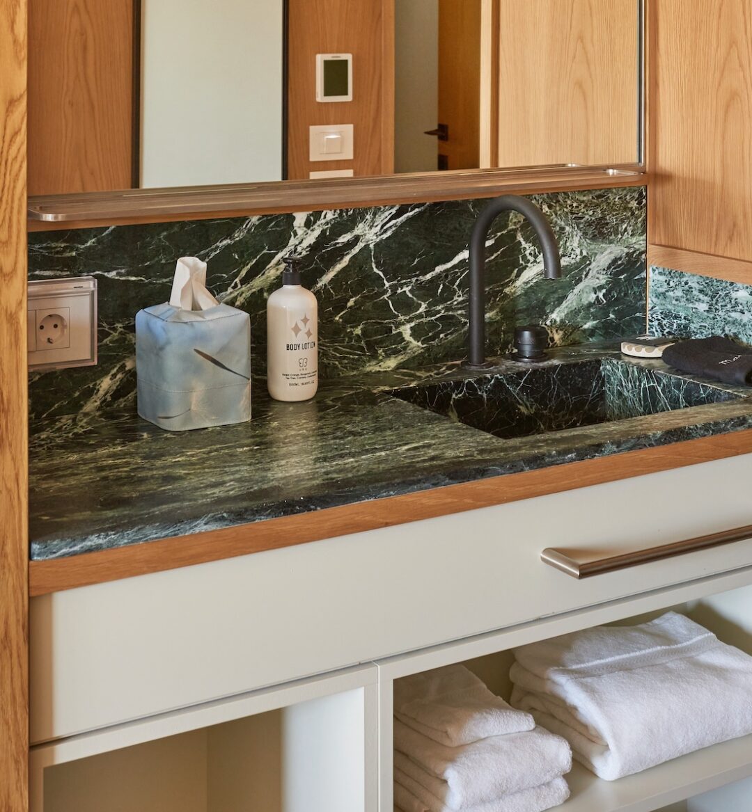 Stylish bathroom showcasing a marble countertop, wooden cabinets, and tall windows that bring in plenty of sunlight.