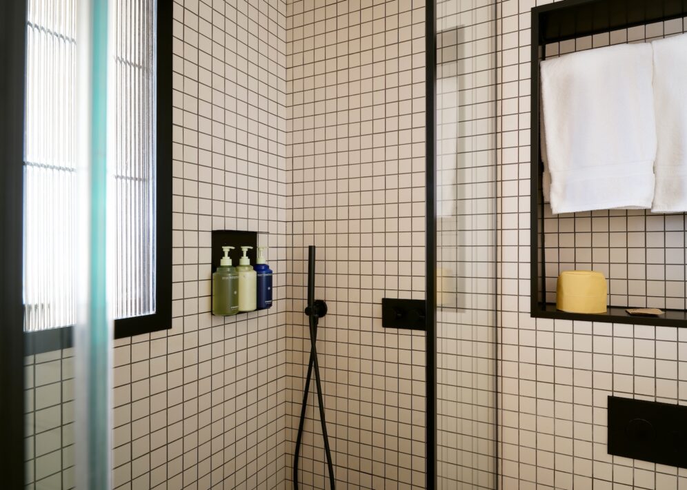 A modern bathroom featuring a walk-in shower with a glazed window and stylish white and black tile flooring.