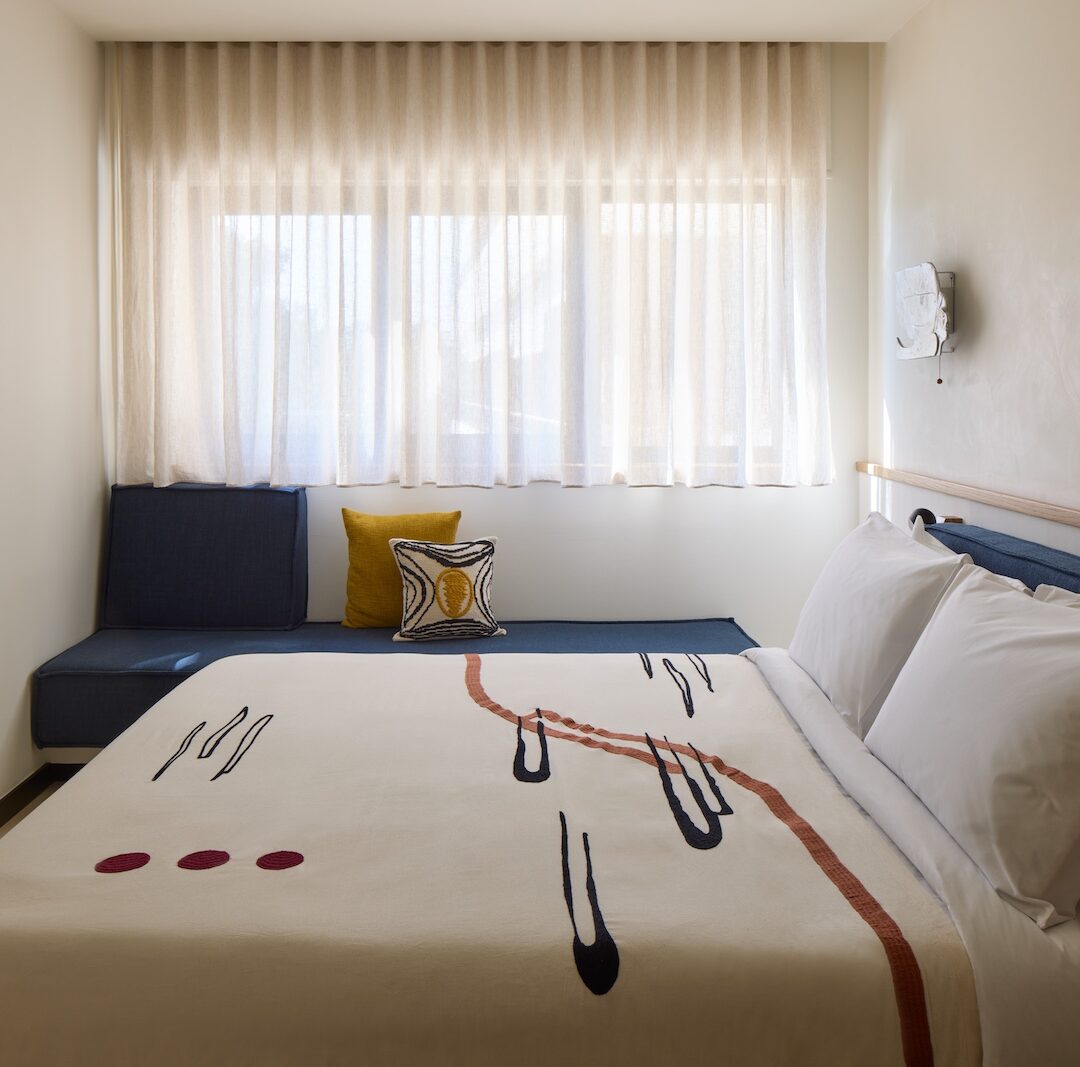 A stylish hotel room showcasing a bed, a television, and a window with sunlight streaming in