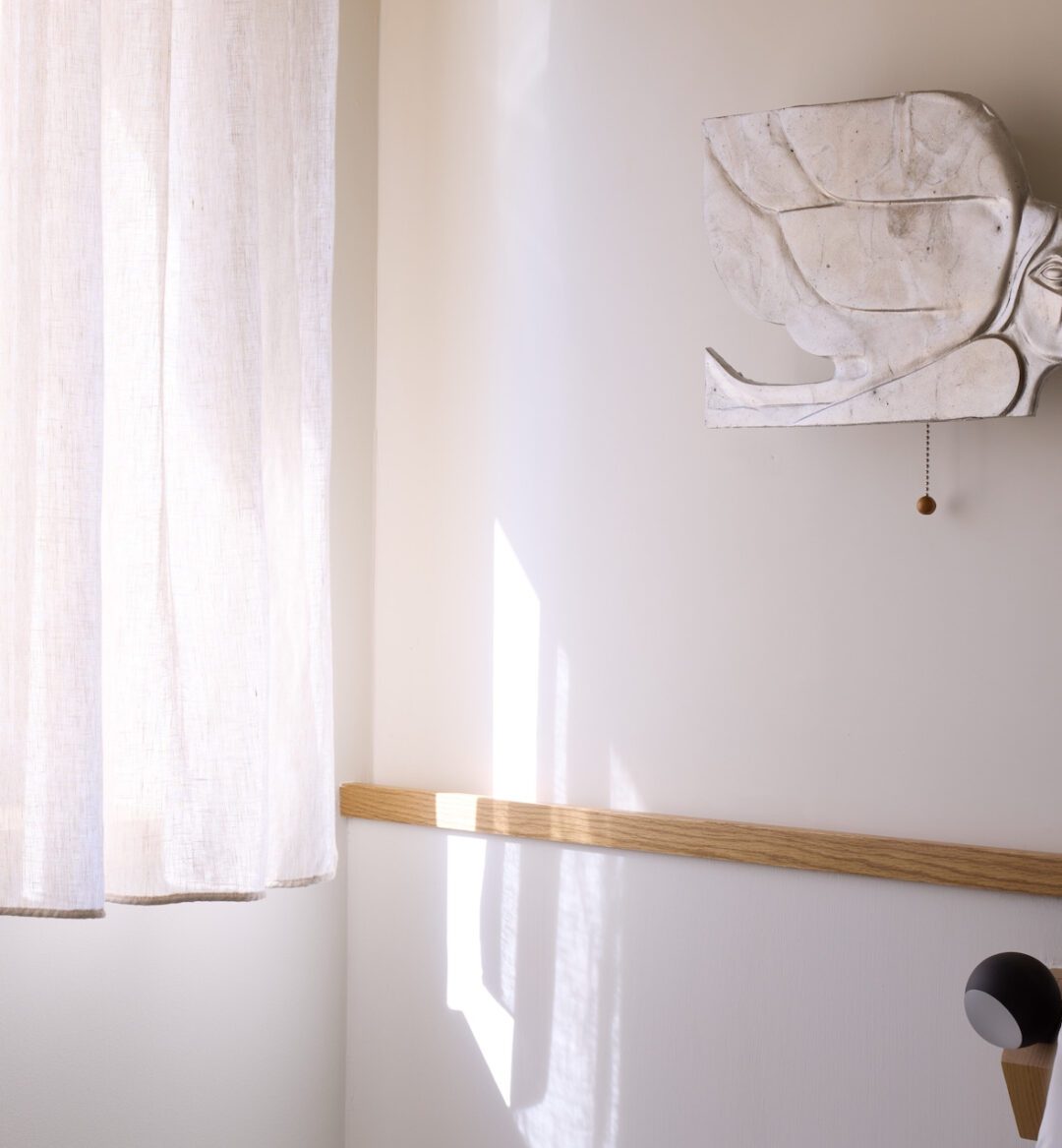 A serene white bed with a soft white pillow, set against a clean white wall.