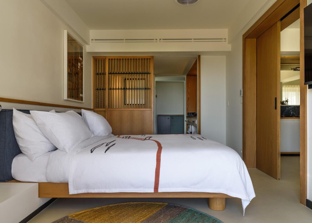 A cozy bed neatly made in a softly lit bedroom, with warm colors and simple decor.