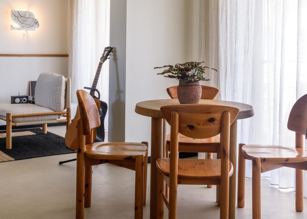 A simple wooden table with chairs set up in a warm, inviting room.