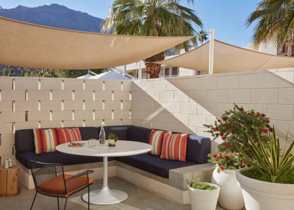 A private patio provides a sofa, table, and chair for outdoor relaxation; a wooden gate provides access to the rest of the outdoors