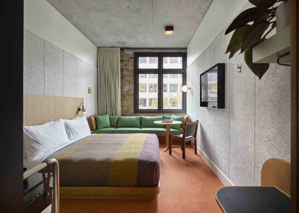 A modern room with red carpeting features a green couch against an exposed brick wall