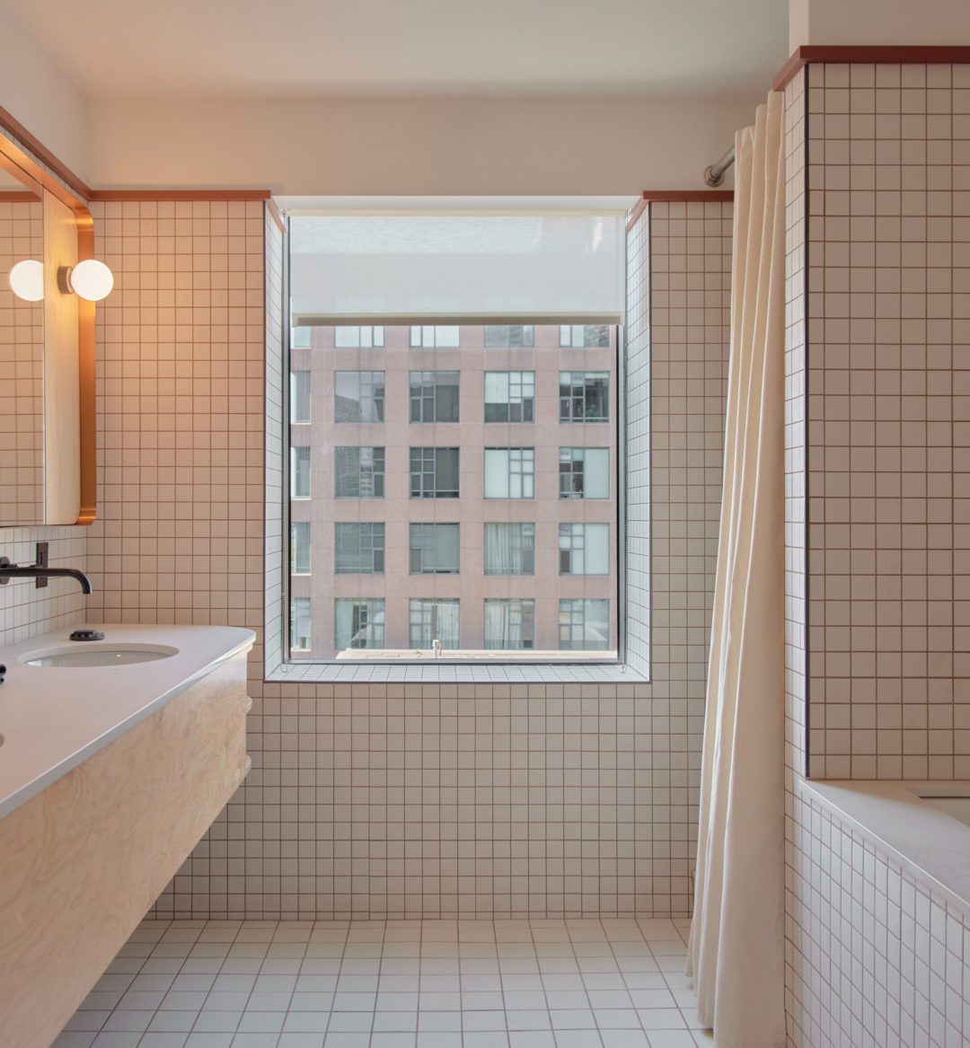 A spacious white tiled bathroom features a deep tub and two vanity areas